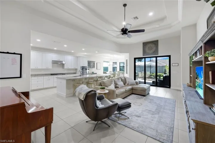 Living area with a ceiling fan, light tile patterned floors, and recessed lighting