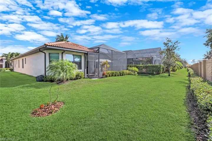 Rear view of property featuring a lawn, a sunroom, a lanai, stucco siding, and a tile roof