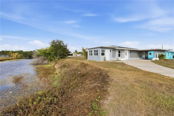View of front of house featuring driveway, an attached carport, a front yard, and a water view