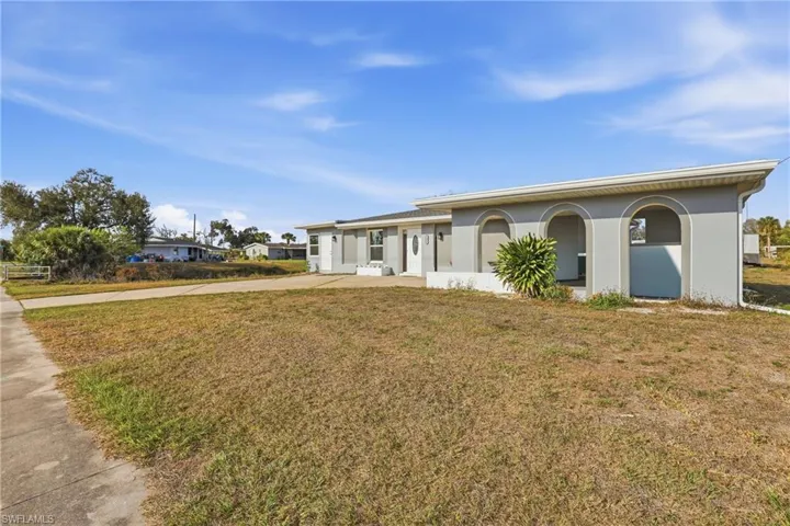 View of front of house with stucco siding, a front lawn, and driveway