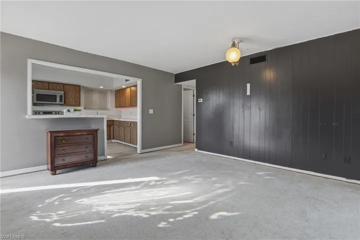 Unfurnished living room featuring wooden walls and light colored carpet