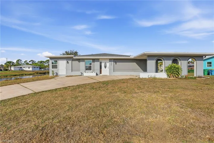 Single story home with a front lawn, stucco siding, and driveway