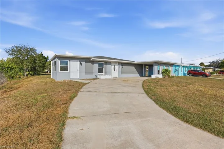 View of front of home featuring a front lawn, driveway, and stucco siding