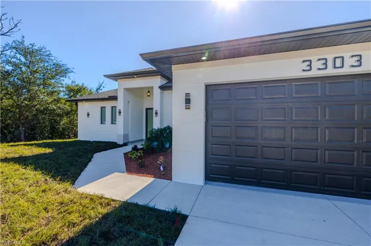 View of front facade with stucco siding, a front lawn, driveway, and an attached garage