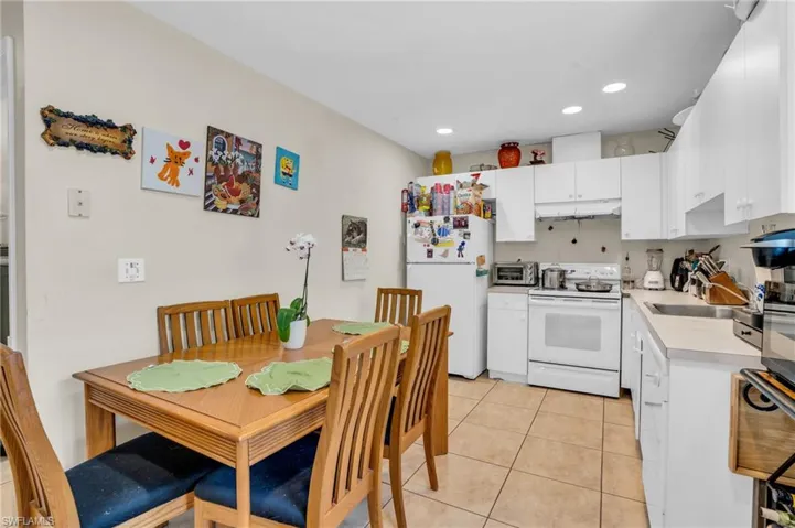 Kitchen featuring white appliances, white cabinets, sink, and light tile floors