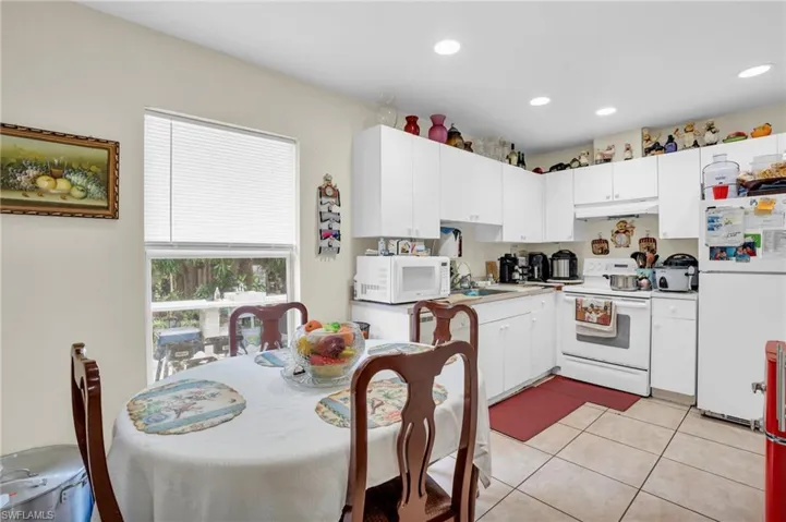 Kitchen featuring sink, white appliances, white cabinetry, and light tile floors