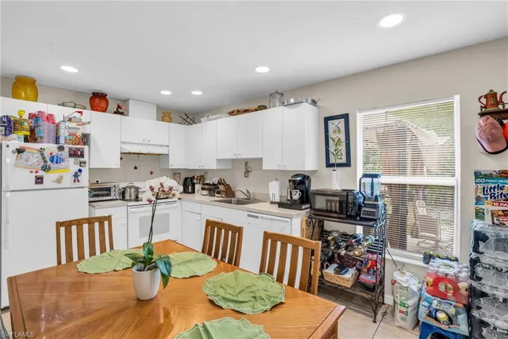 Kitchen featuring white cabinets, sink, white appliances, and light tile flooring
