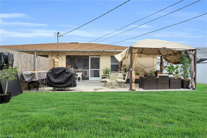 Rear view of property featuring a patio area, a gazebo, an outdoor living space, and a yard