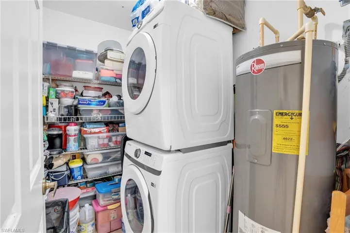 Laundry area featuring stacked washing maching and dryer and water heater