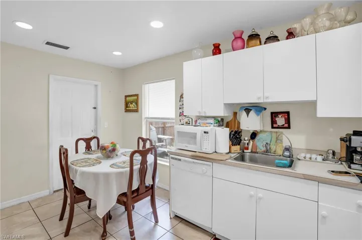 Kitchen featuring white appliances, white cabinets, sink, and light tile floors