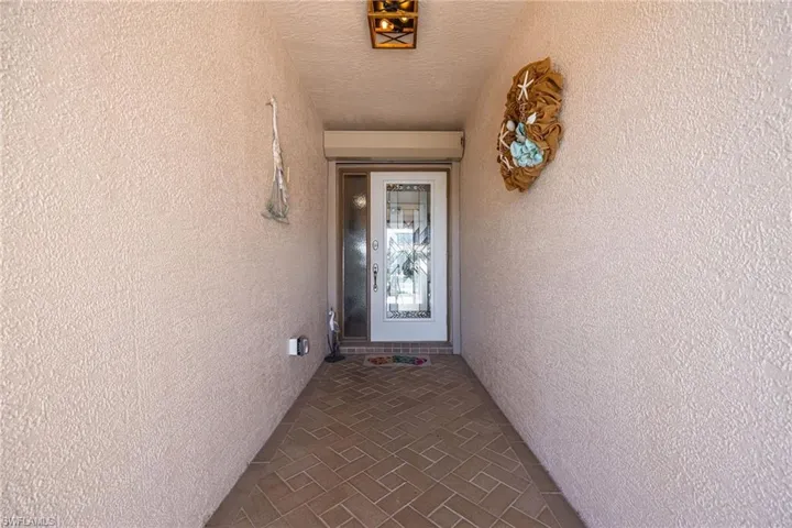 Screened front entry with beautiful decorative glass front door & accordion shutter for added protection