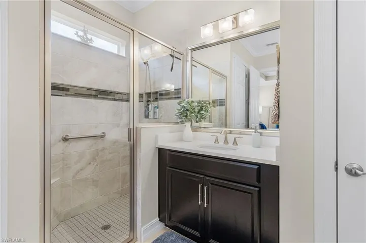 Bathroom featuring an enclosed shower, ornamental molding, and vanity