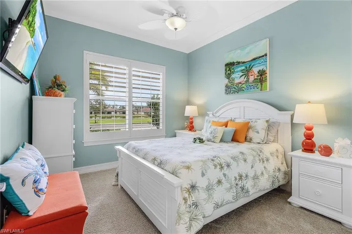 Carpeted bedroom with ceiling fan and crown molding