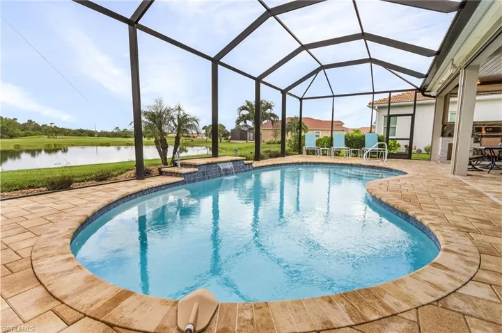 View of pool with a patio area, glass enclosure, and pool water feature
