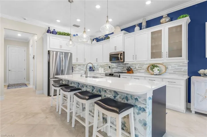 Kitchen featuring sink, stainless steel appliances, decorative light fixtures, and backsplash