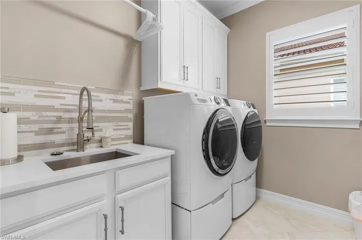 Laundry area with sink, cabinets, independent washer and dryer, and light tile patterned floors