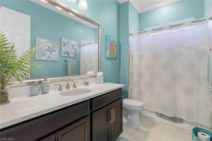 Full bathroom featuring vanity, shower / bath combo with shower curtain, crown molding, tile patterned floors, and toilet