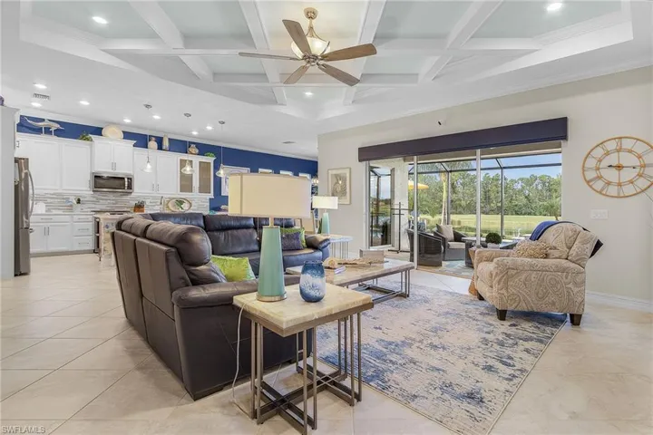 Tiled living room with beamed ceiling, ceiling fan, crown molding, and coffered ceiling