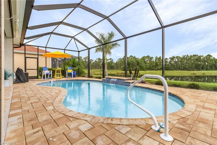 View of swimming pool featuring glass enclosure, pool water feature, and a patio area