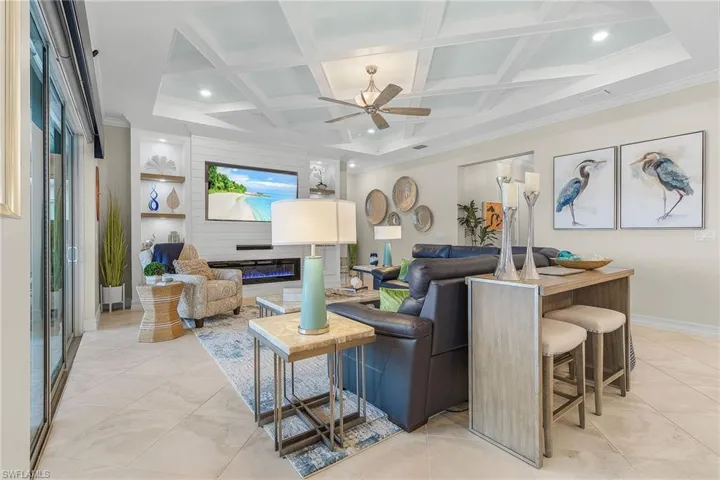 Tiled living room featuring ceiling fan, ornamental molding, beamed ceiling, and coffered ceiling