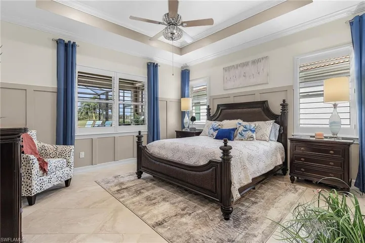 Tiled bedroom with a tray ceiling, ceiling fan, and crown molding