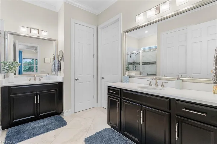 Bathroom featuring a shower with door, crown molding, vanity, and tile patterned floors