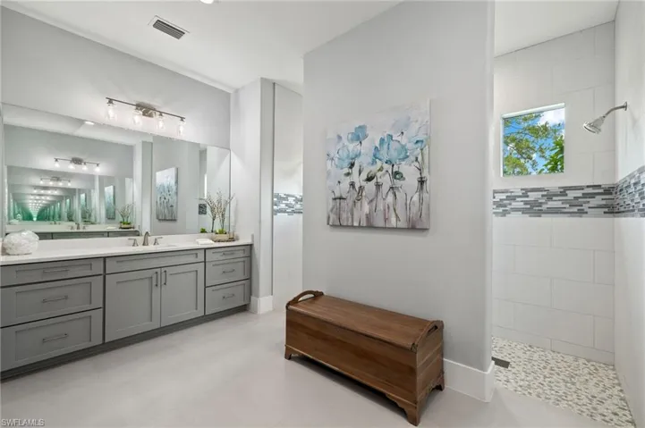 Bathroom with a tile shower, vanity, and tile floors