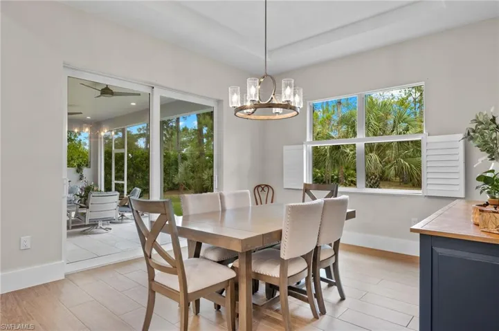 Dining space with a raised ceiling, ceiling fan with notable chandelier, and light hardwood / wood-style flooring