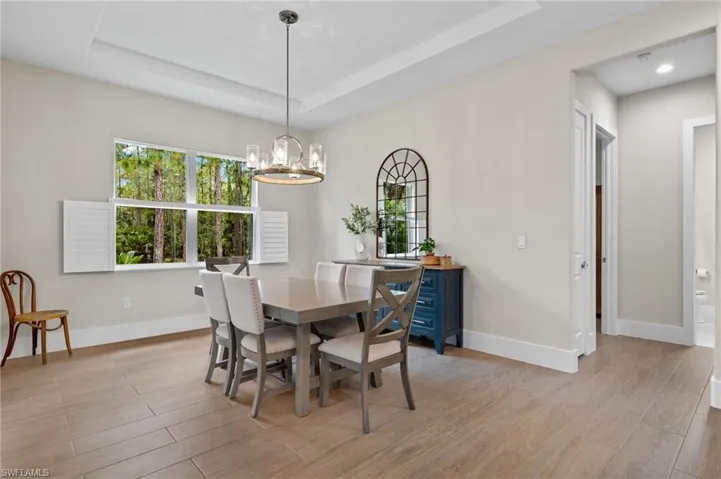 Dining space featuring a notable chandelier, light wood-type flooring, and a raised ceiling