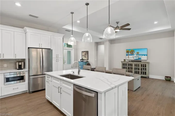 Kitchen featuring a tray ceiling, tasteful backsplash, stainless steel appliances, wood-type flooring, and sink