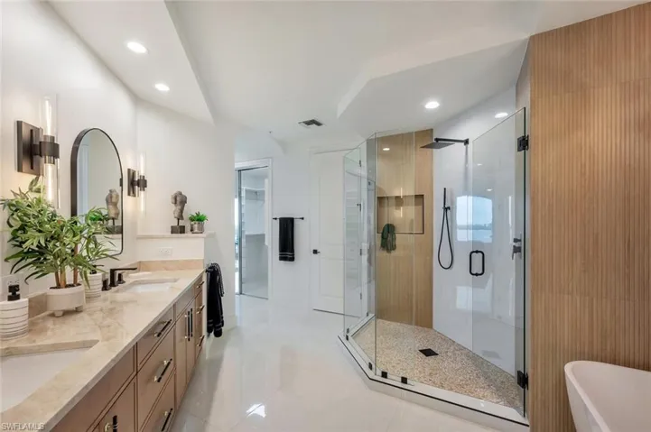 Full bathroom featuring double vanity, a stall shower, a soaking tub, recessed lighting, and light tile patterned floors