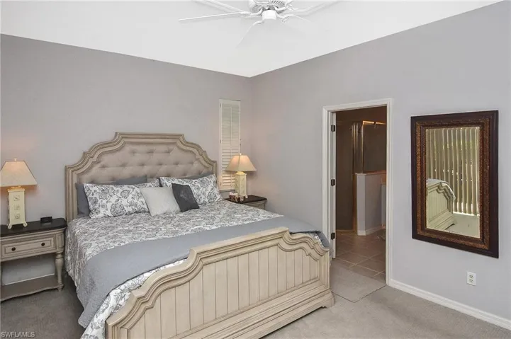 Carpeted bedroom with a ceiling fan and ensuite bath