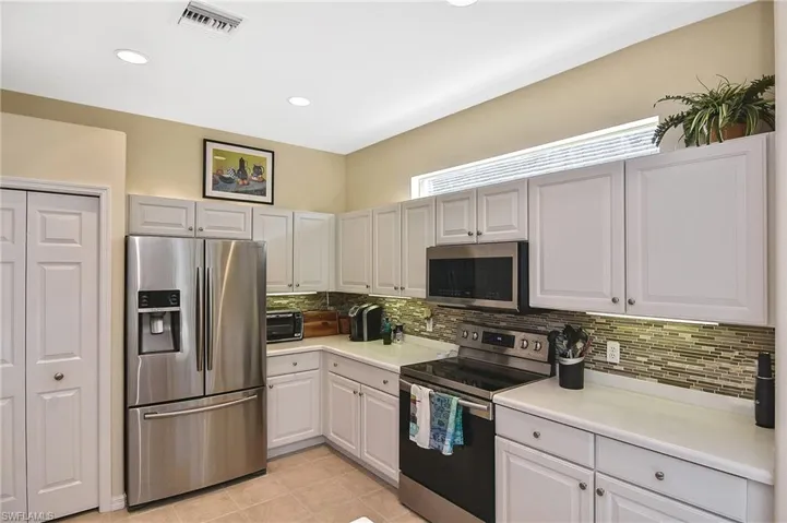 Kitchen with appliances with stainless steel finishes, light countertops, decorative backsplash, light tile patterned floors, and recessed lighting