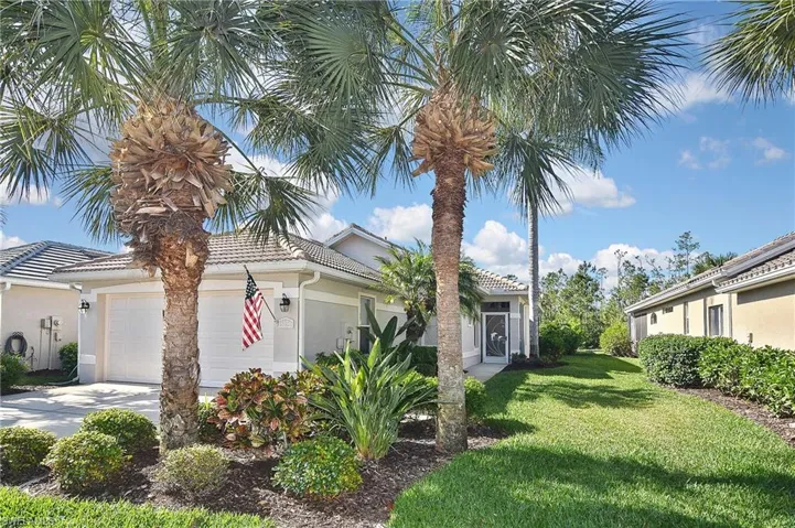 View of front of house with stucco siding, a front lawn, an attached garage, driveway, and a tiled roof