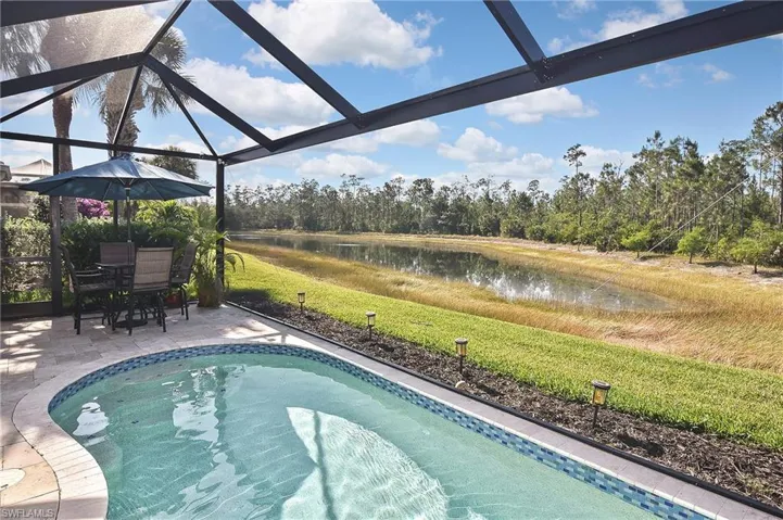 Outdoor pool featuring a water view, a lanai, a lawn, a sunroom, and view of wooded area