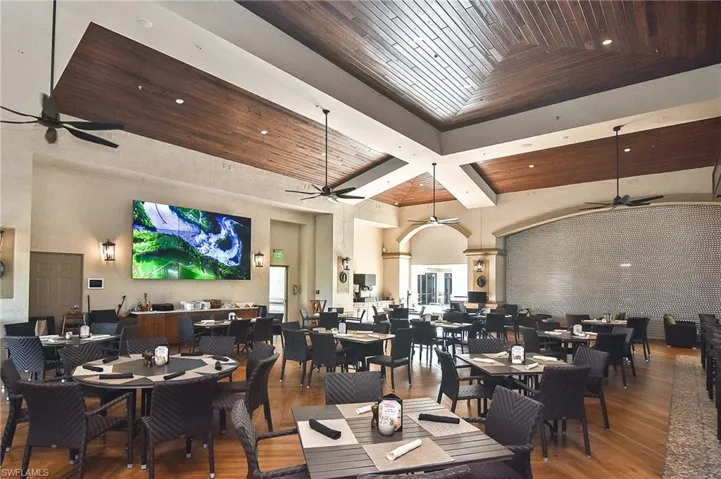 Dining room featuring a ceiling fan, a wood ceiling with exposed beams, wood finished floors, and a high ceiling