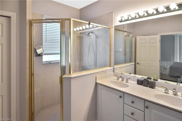 Ensuite bathroom featuring a shower stall and double vanity