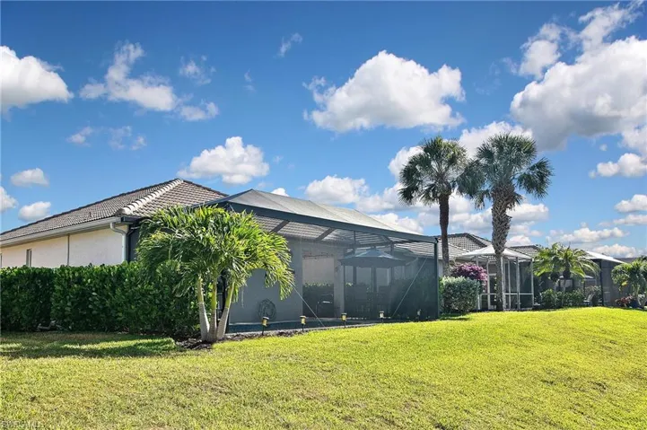 Back of house with glass enclosure, stucco siding, a lawn, and a sunroom