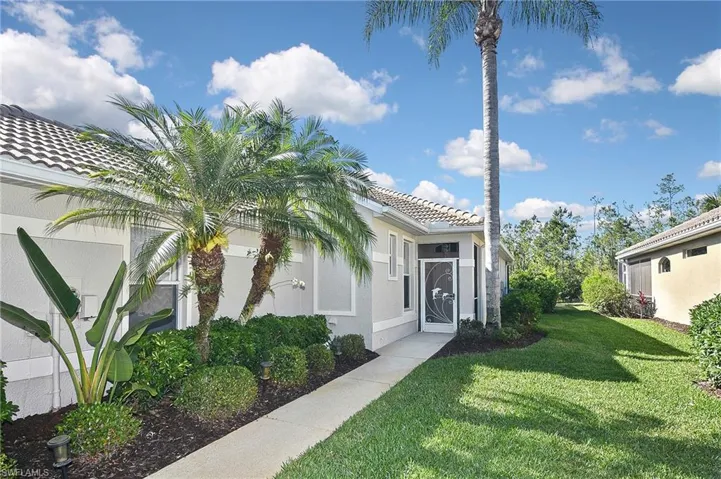 Doorway to property featuring a tile roof, stucco siding, and a lawn