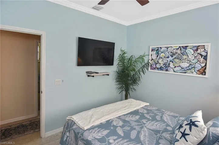 Bedroom with ornamental molding, ceiling fan, and light tile patterned floors