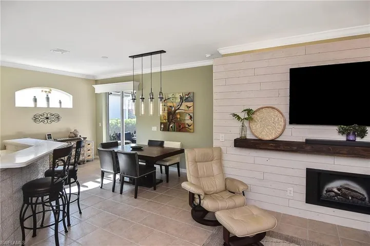 Dining area with light tile patterned flooring, crown molding, and a fireplace