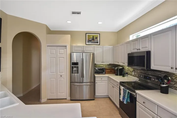 Kitchen with appliances with stainless steel finishes, tasteful backsplash, light countertops, light tile patterned floors, and recessed lighting