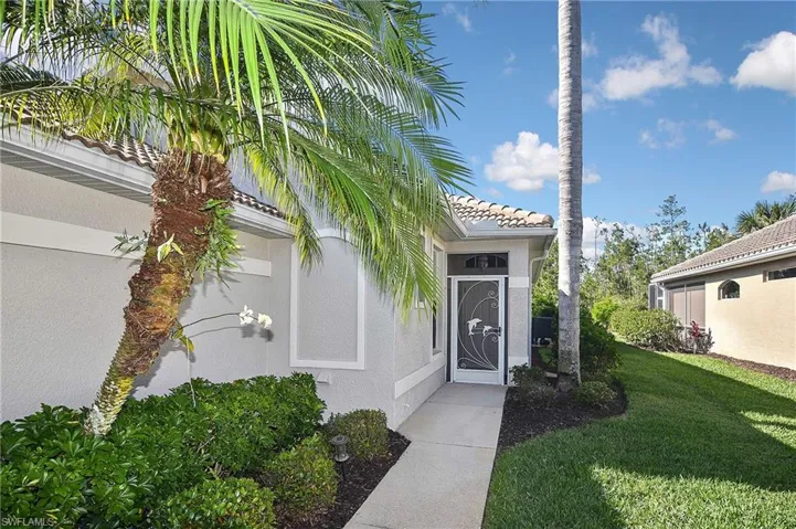 View of exterior entry with stucco siding, a lawn, and a tiled roof