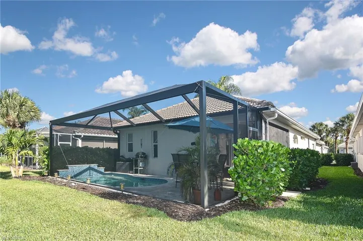 Rear view of property with a lanai, a sunroom, a yard, and an outdoor pool
