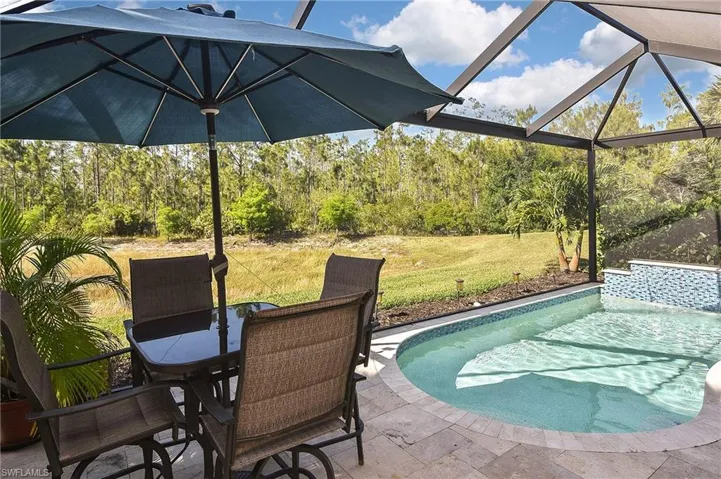 Outdoor pool with glass enclosure, a yard, a patio area, a sunroom, and outdoor dining space