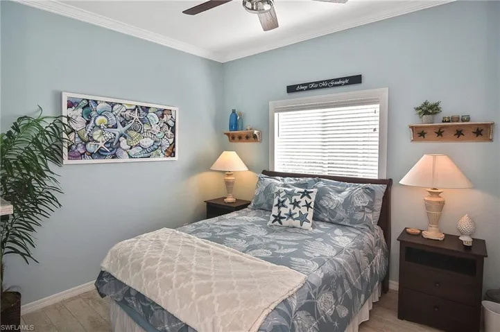 Bedroom featuring crown molding, wood finished floors, and a ceiling fan