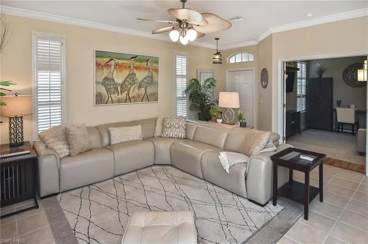 Tiled living room featuring crown molding and a ceiling fan