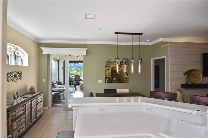 Kitchen with decorative light fixtures, crown molding, light tile patterned flooring, and light countertops