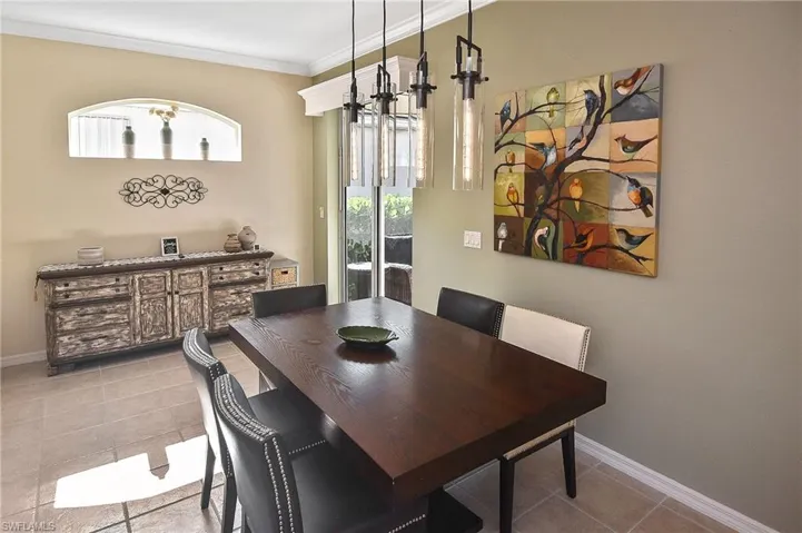 Dining room with light tile patterned floors, crown molding, and a chandelier