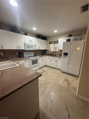 Kitchen with stove, fridge, dark countertops, decorative backsplash, and recessed lighting